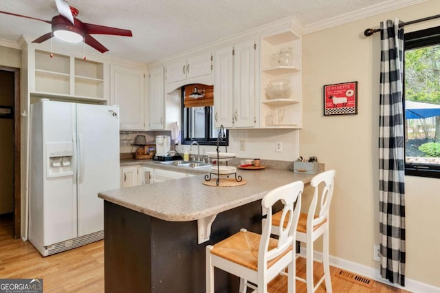 2796 County Line Rd NW, Acworth, GA 30101 - kitchen with white fridge with ice dispenser, open shelves, a peninsula, light wood finished floors, and crown molding