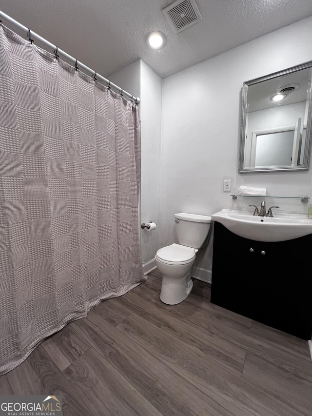 2976 Twin Pine Rd, Thomson, GA 30824 - full bath featuring toilet, wood finished floors, vanity, a textured ceiling, and a shower with shower curtain