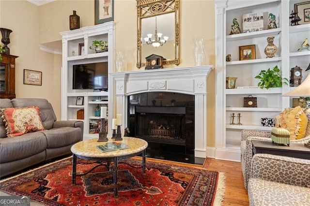 4115 Gold Mill Rdg, Canton, GA 30114 - living area featuring built in shelves, wood finished floors, a fireplace with flush hearth, a chandelier, and crown molding