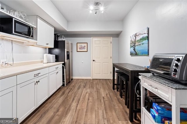 4115 Gold Mill Rdg, Canton, GA 30114 - kitchen featuring stainless steel appliances, light wood-type flooring, white cabinetry, light countertops, and baseboards