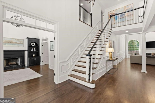 5120 Falcon Chase Ln, Atlanta, GA 30342 - stairs with a fireplace with flush hearth, a high ceiling, a decorative wall, wood finished floors, and ornate columns