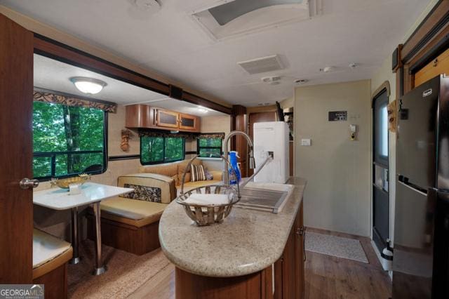 44 11th St, Ellijay, GA 30540 - kitchen with freestanding refrigerator, wood finished floors, light countertops, and brown cabinets