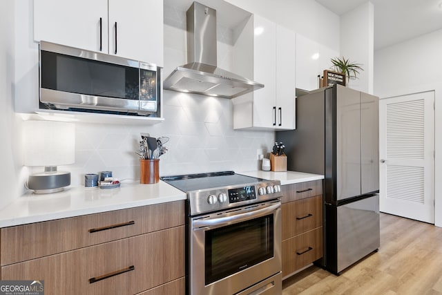 112 Rogers St NE Unit 410, Atlanta, GA 30317 - kitchen featuring exhaust hood, appliances with stainless steel finishes, white cabinetry, light countertops, and light wood-style flooring
