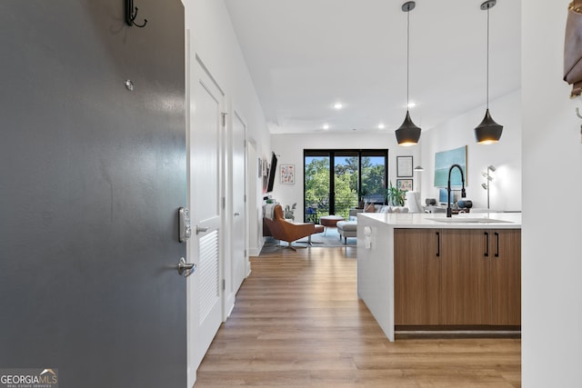 112 Rogers St NE Unit 410, Atlanta, GA 30317 - kitchen with a sink, light countertops, light wood-style flooring, brown cabinets, and open floor plan