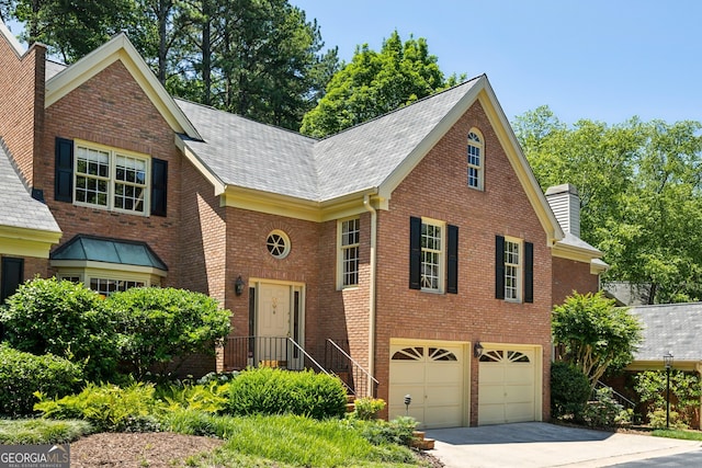 51 Ivy Chase NE, Atlanta, GA 30342 - view of front facade with a chimney, concrete driveway, brick siding, an attached garage, and a shingled roof