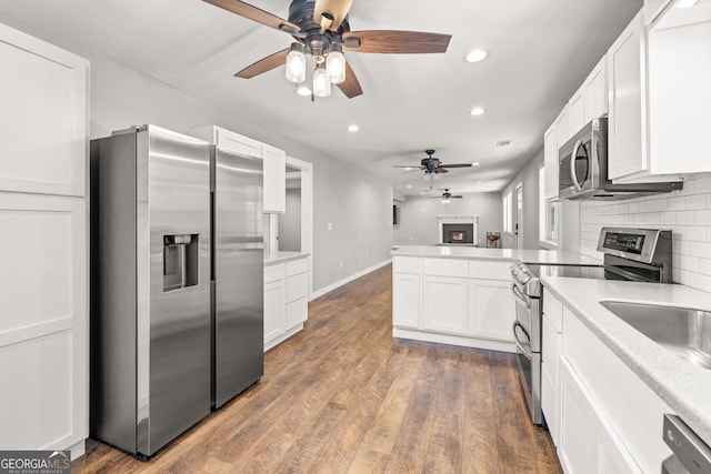 1935 Sam Bell Rd, Clarkesville, GA 30523 - kitchen featuring appliances with stainless steel finishes, ceiling fan, a lit fireplace, recessed lighting, and a peninsula