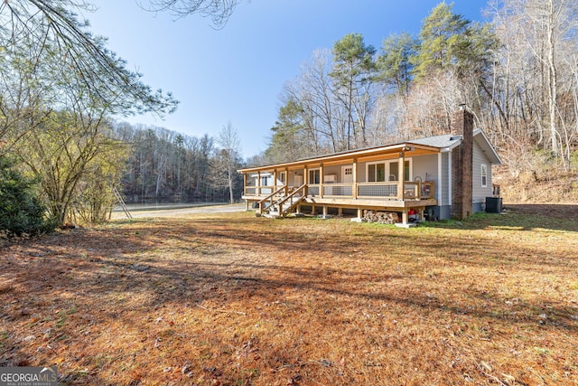 1935 Sam Bell Rd, Clarkesville, GA 30523 - view of front facade with covered porch, a chimney, a view of trees, and a front yard