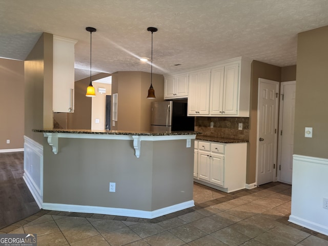 1280 Waterwood Dr, Loganville, GA 30052 - kitchen with freestanding refrigerator, a kitchen breakfast bar, white cabinetry, a peninsula, and a textured ceiling