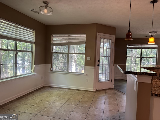 1280 Waterwood Dr, Loganville, GA 30052 - unfurnished dining area with wainscoting, light tile patterned floors, and a textured ceiling