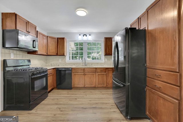 4516 Creekwood Cir NW, Kennesaw, GA 30152 - kitchen with black appliances, a sink, light wood-type flooring, brown cabinetry, and tasteful backsplash