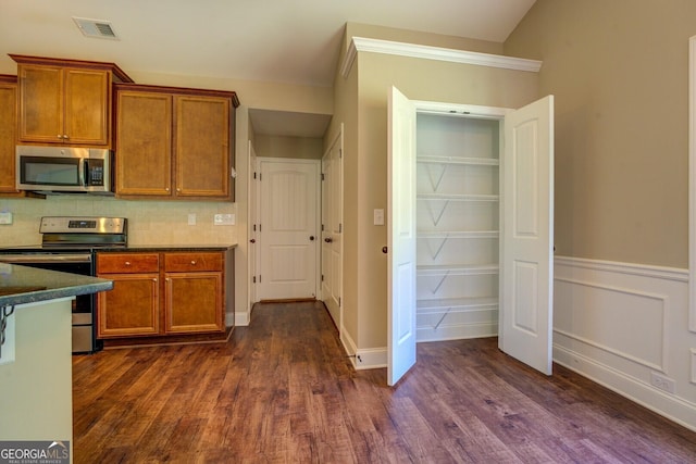 70 Country Meadows Ln, Covington, GA 30014 - kitchen featuring stainless steel appliances, brown cabinetry, dark countertops, and dark wood finished floors