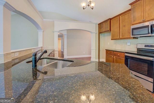70 Country Meadows Ln, Covington, GA 30014 - kitchen featuring appliances with stainless steel finishes, decorative columns, a sink, brown cabinetry, and crown molding