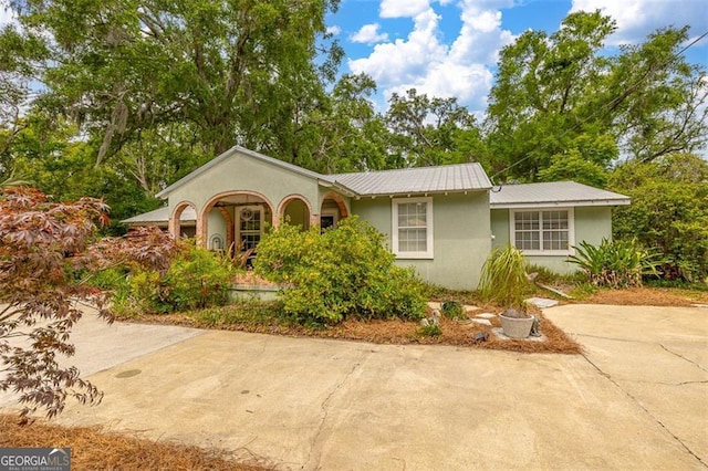 3 Stewart Ave, Saint Simons, GA 31522 - view of front facade featuring stucco siding, metal roof, and driveway