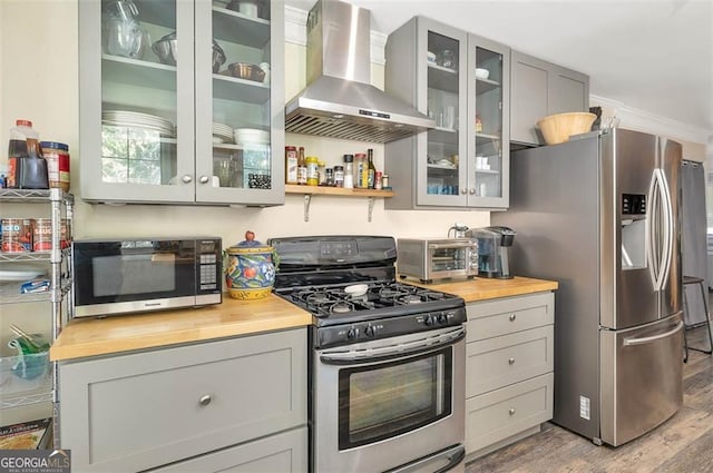 3 Stewart Ave, Saint Simons, GA 31522 - kitchen featuring appliances with stainless steel finishes, wood counters, wall chimney range hood, wood finished floors, and gray cabinets