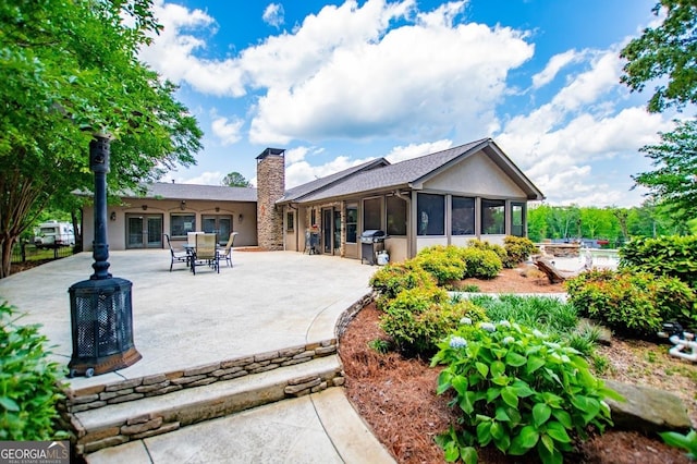 1050 Denton Rd, Douglasville, GA 30134 - back of property with french doors, a chimney, a patio area, stucco siding, and a sunroom
