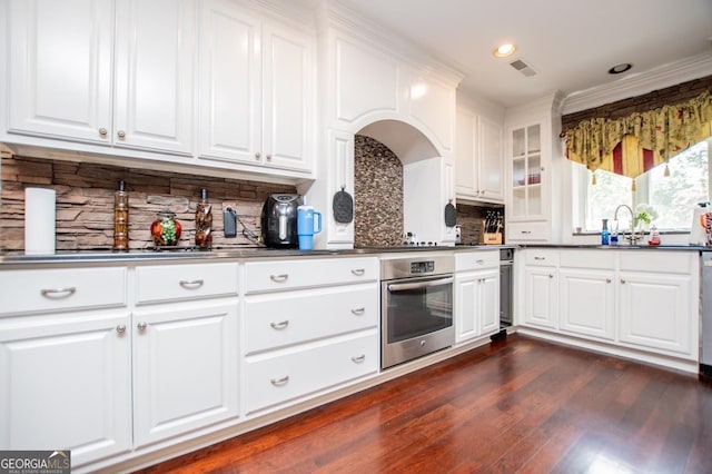 1050 Denton Rd, Douglasville, GA 30134 - kitchen featuring oven, dark countertops, dark wood-style flooring, tasteful backsplash, and white cabinets