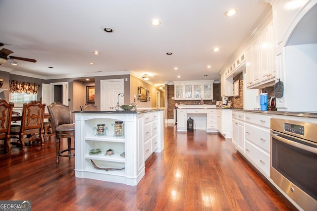 1050 Denton Rd, Douglasville, GA 30134 - kitchen with stainless steel oven, open shelves, ornamental molding, white cabinets, and dark countertops