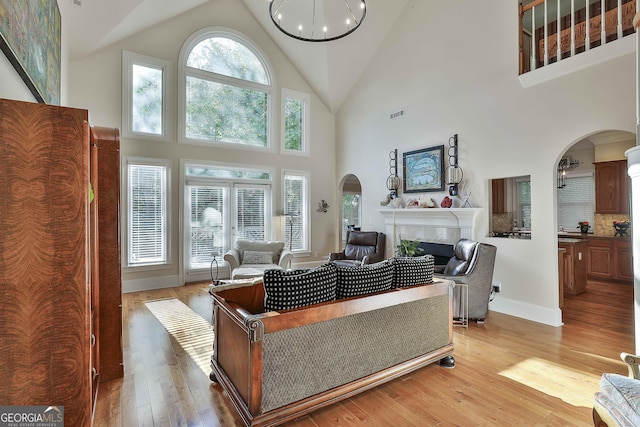 1000 Pleasance Grv, Peachtree City, GA 30269 - living area featuring high vaulted ceiling, arched walkways, a tile fireplace, light wood-style floors, and baseboards