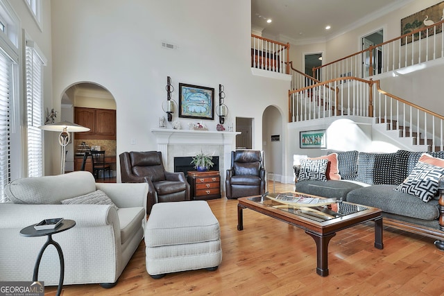 1000 Pleasance Grv, Peachtree City, GA 30269 - living area with a towering ceiling, arched walkways, stairway, light wood-style floors, and a premium fireplace