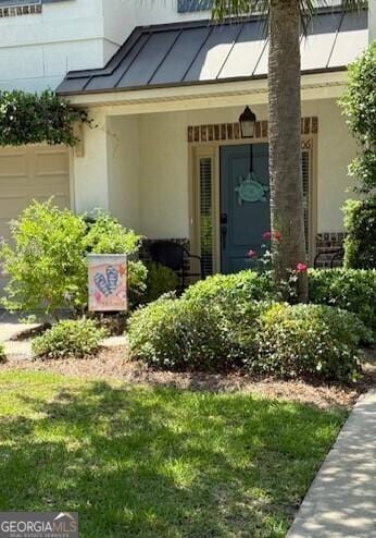 306 Reserve Ln, Saint Simons, GA 31522 - entrance to property featuring stucco siding, a garage, and a lawn
