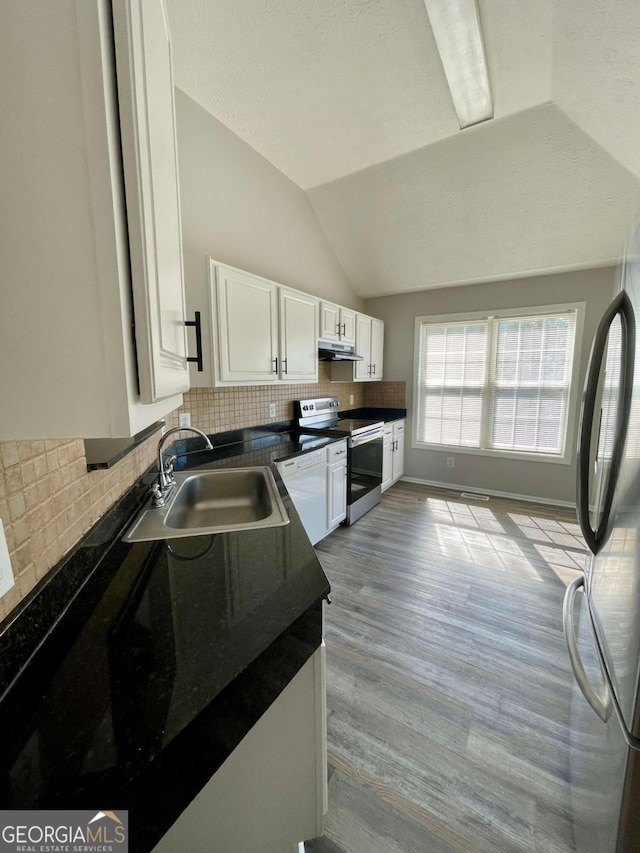 350 Fall View Ct, Winder, GA 30680 - kitchen featuring appliances with stainless steel finishes, dark countertops, lofted ceiling, white cabinetry, and under cabinet range hood