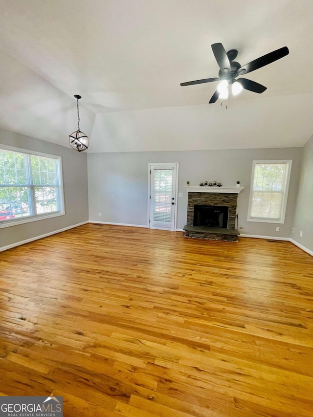 350 Fall View Ct, Winder, GA 30680 - unfurnished living room with lofted ceiling, light wood-style flooring, ceiling fan, a stone fireplace, and a chandelier