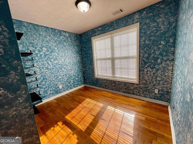 350 Fall View Ct, Winder, GA 30680 - spare room with wood-type flooring, wallpapered walls, and a textured ceiling