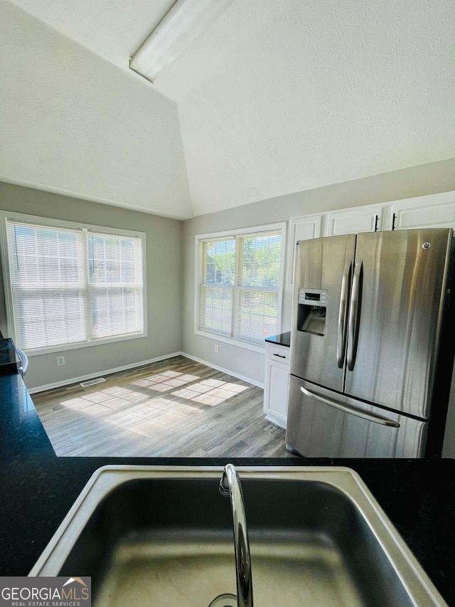350 Fall View Ct, Winder, GA 30680 - kitchen featuring stainless steel refrigerator with ice dispenser, lofted ceiling, dark countertops, white cabinets, and wood finished floors