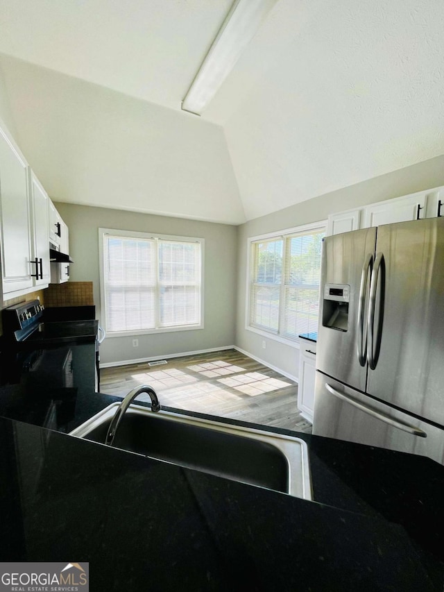 350 Fall View Ct, Winder, GA 30680 - kitchen featuring stainless steel refrigerator with ice dispenser, electric range, white cabinets, vaulted ceiling, and under cabinet range hood