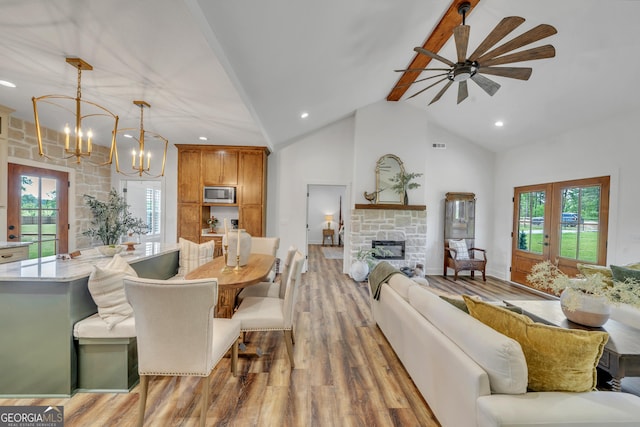 1354 Lakeway Rd, East Dublin, GA 31027 - living room featuring a chandelier, beam ceiling, light wood finished floors, a stone fireplace, and plenty of natural light