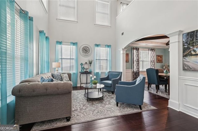 1017 Preserve Park Dr, Loganville, GA 30052 - living area featuring ornate columns, arched walkways, hardwood / wood-style flooring, a towering ceiling, and a wainscoted wall