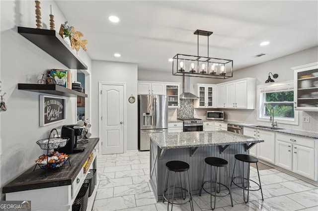 1017 Preserve Park Dr, Loganville, GA 30052 - kitchen with stainless steel appliances, light marble finish floors, wall chimney exhaust hood, a kitchen bar, and recessed lighting