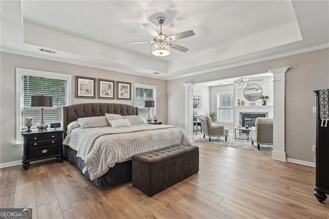 1017 Preserve Park Dr, Loganville, GA 30052 - bedroom featuring a raised ceiling, decorative columns, hardwood / wood-style floors, and multiple windows