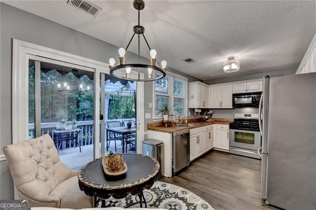 10000 Barston Ct, Johns Creek, GA 30022 - kitchen with appliances with stainless steel finishes, white cabinets, dark wood-style flooring, a chandelier, and a textured ceiling