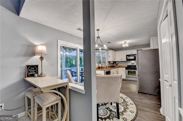 10000 Barston Ct, Johns Creek, GA 30022 - kitchen featuring appliances with stainless steel finishes, white cabinets, dark wood-style floors, a textured ceiling, and a peninsula
