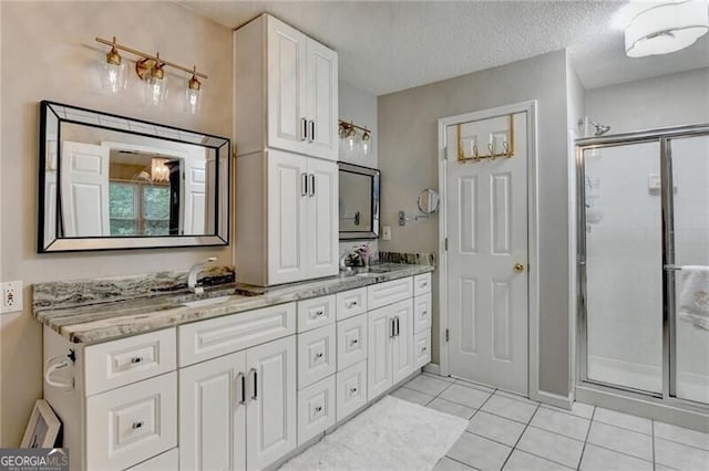 10000 Barston Ct, Johns Creek, GA 30022 - bathroom featuring a shower stall, double vanity, tile patterned flooring, and a textured ceiling