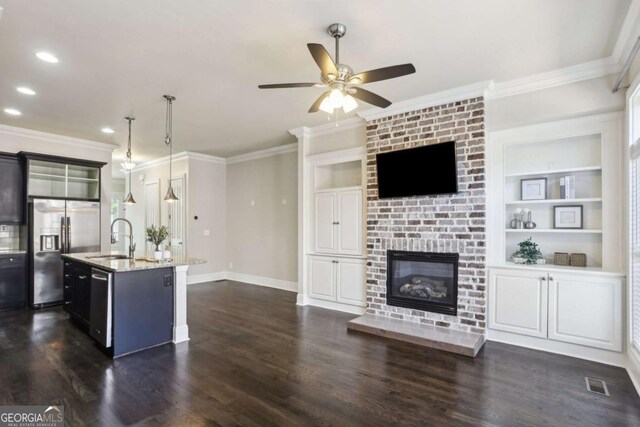 345 Alderwood Ln, Sandy Springs, GA 30328 - kitchen featuring appliances with stainless steel finishes, ornamental molding, ceiling fan, light stone counters, and a kitchen island with sink