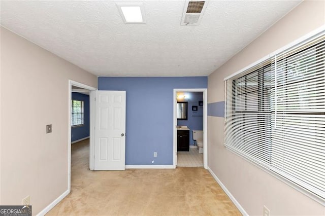 916 Forest Pointe Way, Jonesboro, GA 30238 - unfurnished bedroom featuring baseboards, light colored carpet, ensuite bathroom, and a textured ceiling