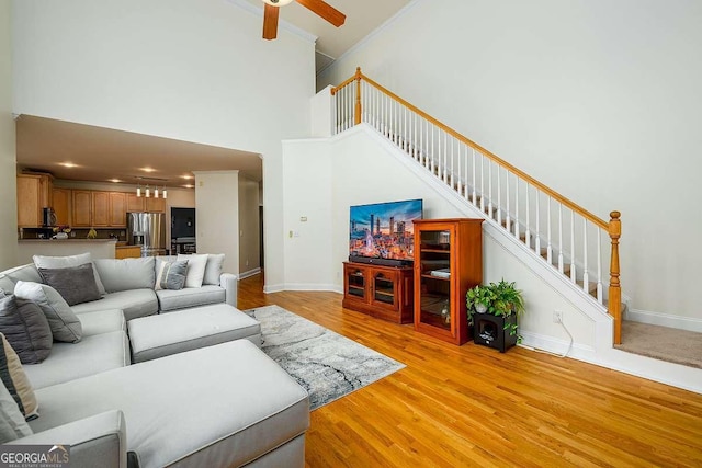 2484 Mossy Branch Dr, Snellville, GA 30078 - living area with stairway, a high ceiling, light wood-style floors, a ceiling fan, and baseboards