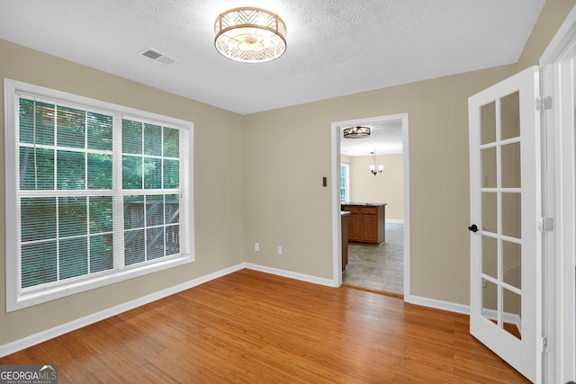 4000 Mcpherson Dr, Acworth, GA 30101 - spare room with light wood-type flooring, a chandelier, and a textured ceiling