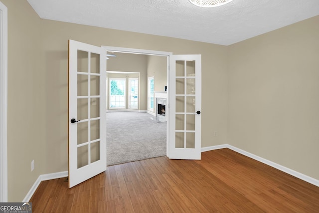4000 Mcpherson Dr, Acworth, GA 30101 - spare room with french doors, wood finished floors, and a fireplace with flush hearth
