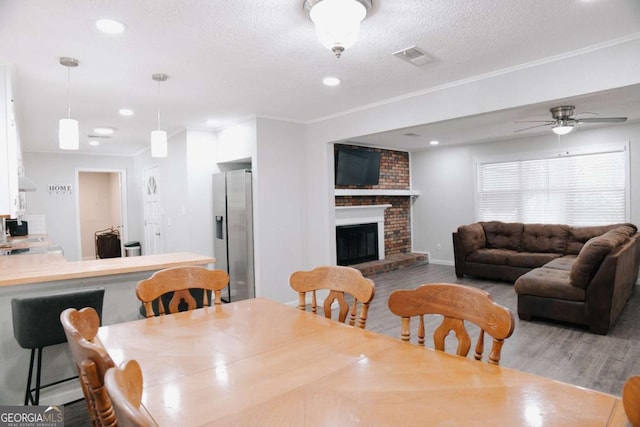 435 Goss Rd, Epworth, GA 30541 - dining space with wood finished floors, ceiling fan, a textured ceiling, a fireplace, and crown molding