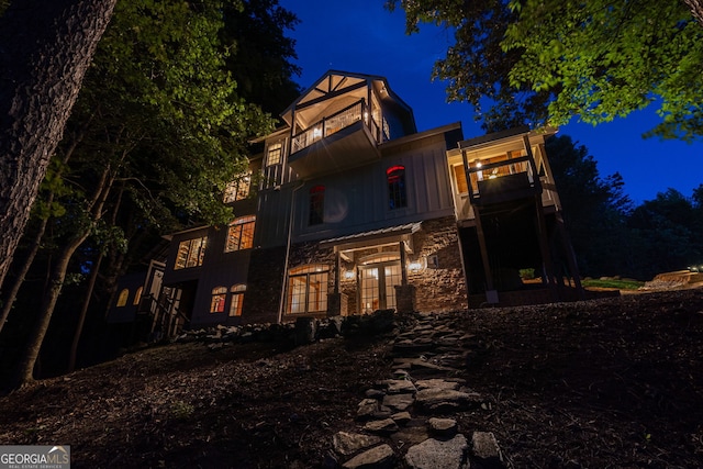 4317 Harold Whelchel Rd, Gainesville, GA 30506 - back of house at twilight with french doors, stone siding, a balcony, and board and batten siding