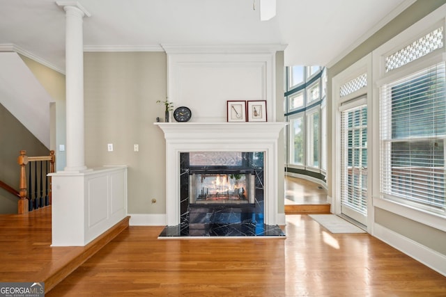 2871 Trailing Ivy Way, Buford, GA 30519 - unfurnished living room featuring wood finished floors, a tiled fireplace, ornate columns, and plenty of natural light