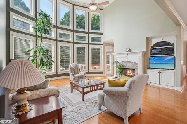 2871 Trailing Ivy Way, Buford, GA 30519 - living area with a stone fireplace, a towering ceiling, light wood-type flooring, and a ceiling fan