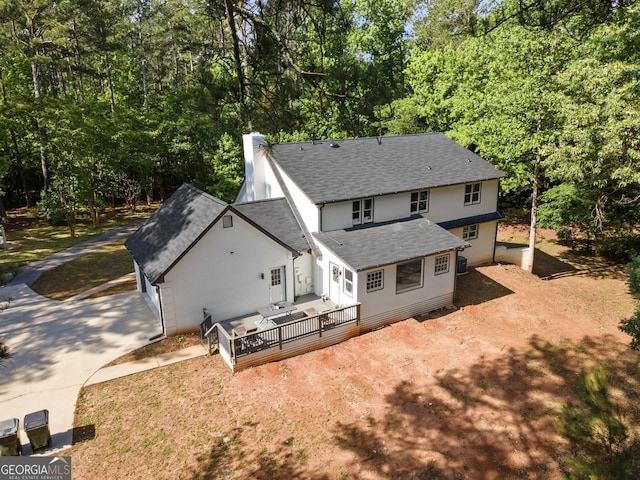 1143 Mcgarity Rd, Mcdonough, GA 30252 - back of house with roof with shingles, concrete driveway, a deck, a chimney, and view of wooded area