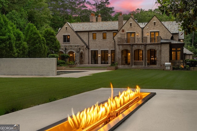 4560 Harris Trl, Atlanta, GA 30327 - back of property featuring stone siding, a fire pit, a balcony, a chimney, and a lawn