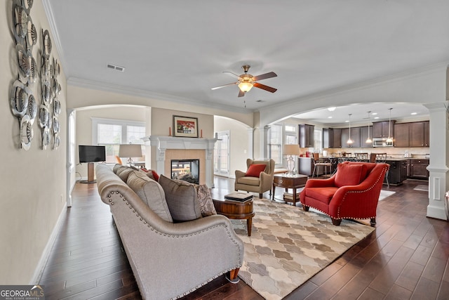 1516 Winward Dr, Locust Grove, GA 30248 - living room with arched walkways, ornate columns, ceiling fan, a fireplace, and ornamental molding