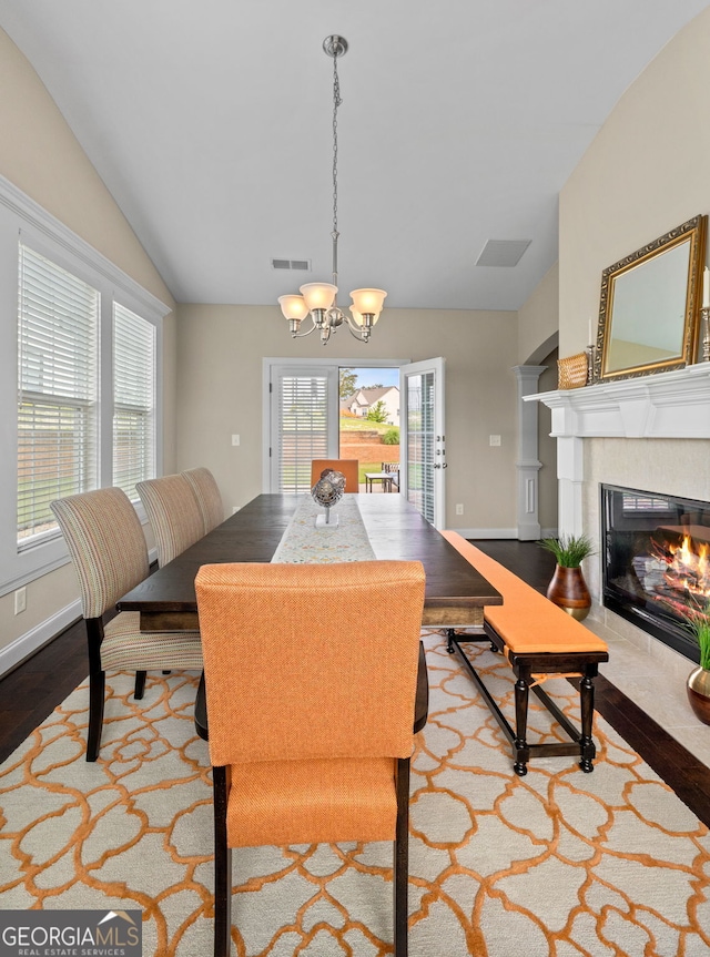 1516 Winward Dr, Locust Grove, GA 30248 - dining room featuring vaulted ceiling, a chandelier, wood finished floors, a fireplace with flush hearth, and baseboards