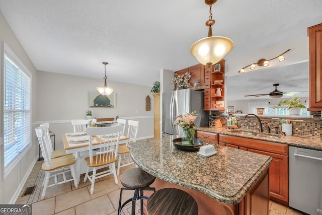 2006 Carrollton Hwy, Temple, GA 30179 - kitchen featuring appliances with stainless steel finishes, a textured ceiling, backsplash, brown cabinetry, and a sink